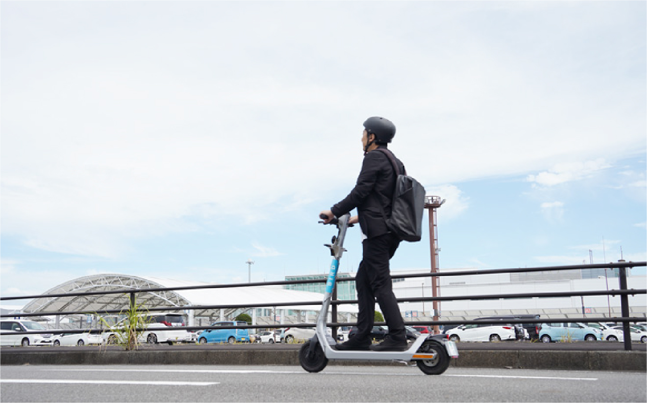 電動キックスクーターに乗って都市の道路を移動するビジネスマン